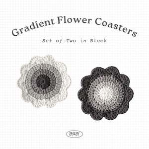 May include: Two black crochet flower coasters with a gradient design. The coasters are circular with a scalloped edge. The text "Gradient Flower Coasters" and "Set of Two in Black" are displayed above the coasters.