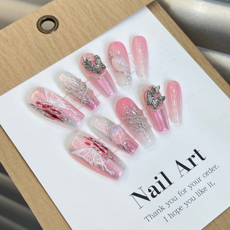 May include: Pink and white ombre press-on nails with silver butterfly and chain accents.  "Nail Art" text is written on the white background.  "Thank you for your order. I hope you like it." is written below the text.