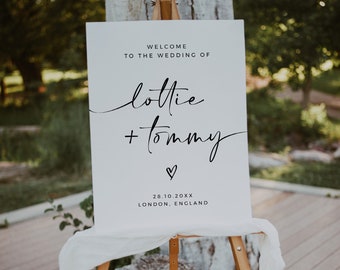 May include: White wedding welcome sign with black text. The sign reads "Welcome to the wedding of Lottie + Tommy" with a small heart symbol and the date "28.10.20XX" and location "London, England".
