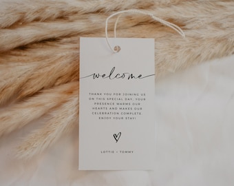 Op de afbeelding: Een wit welkomsbord met zwarte tekst die "welcome", "Thank you for joining us on this special day, your presence warms our hearts and makes our celebration complete. Enjoy your stay!" en "Lottie Tommy" luidt. Onder de tekst is een klein hartje getekend.
