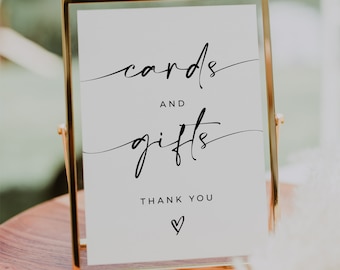 May include: A gold-framed sign with white background and black text that reads "cards and gifts thank you" with a heart symbol.