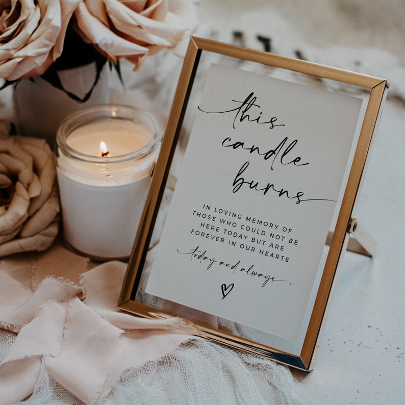 May include: A gold-framed sign with a white background and black text that reads "this candle burns in loving memory of those who could not be here today but are forever in our hearts today and always" with a small heart symbol.