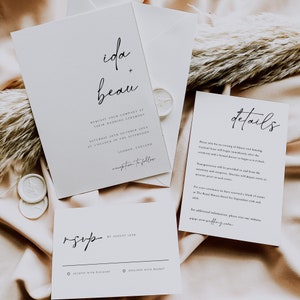 May include: A white wedding invitation with black calligraphy text. The invitation reads "ida + beau" and includes the wedding date, time, and location. The RSVP card is also included with the text "rsvp by August 18th".