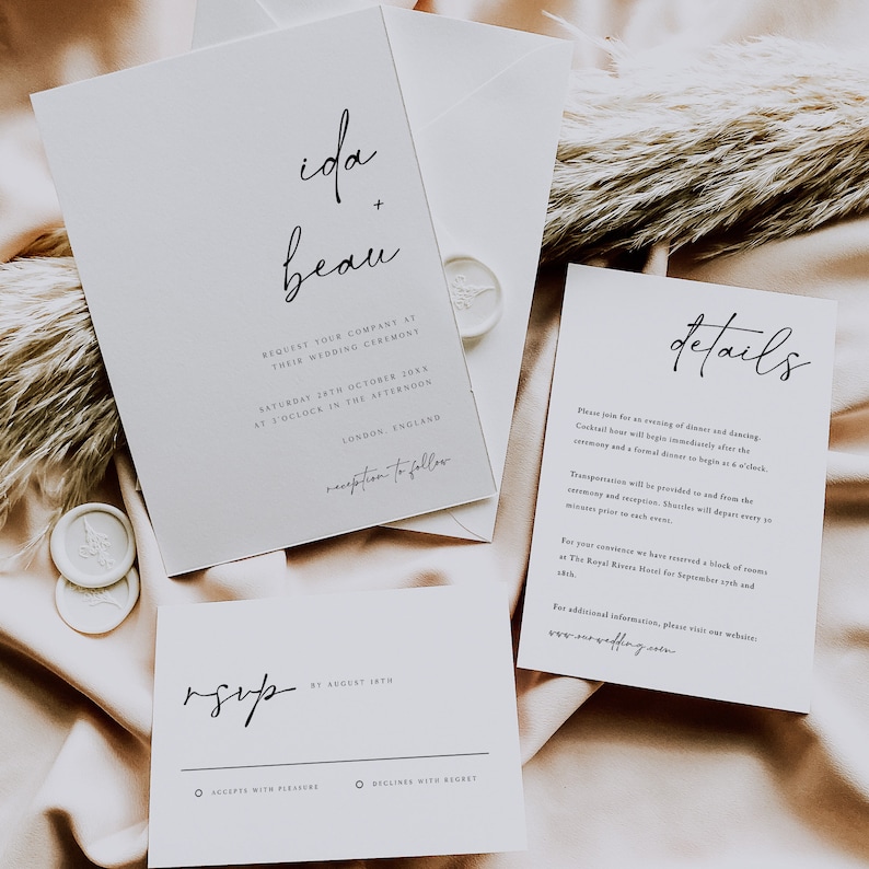 May include: A white wedding invitation with black calligraphy text. The invitation reads "ida + beau" and includes the wedding date, time, and location. The RSVP card is also included with the text "rsvp by August 18th".