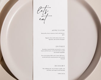 May include: A white menu card with the words "let's eat" written in black cursive script. The menu lists appetizers, entrees, and desserts. The menu is on a light pink plate.