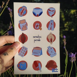 Könnte beinhalten: Eine weiße Karte mit Illustrationen von Menstruationsprodukten und verwandten Artikeln, wie Binden, Unterwäsche und einer Menstruationstasse. Der Satz "normalize periods" steht auf der Karte. Die Karte wird vor einem natürlichen Hintergrund gehalten.