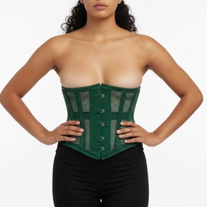 Puede incluir: Un corsé verde oscuro con un diseño de malla. El corsé tiene una silueta estructurada con paneles verticales y horizontales. Cuenta con una fila de pequeños cierres plateados en la parte delantera.
