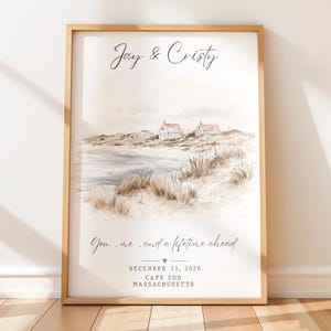 Peut inclure: Une impression aquarelle encadrée représentant un paysage côtier avec des maisons, des dunes de sable et des herbes de plage. Le texte indique Jay & Cristy, You, me, and a lifetime ahead, December 15, 2026, et Cape Cod Massachusetts.