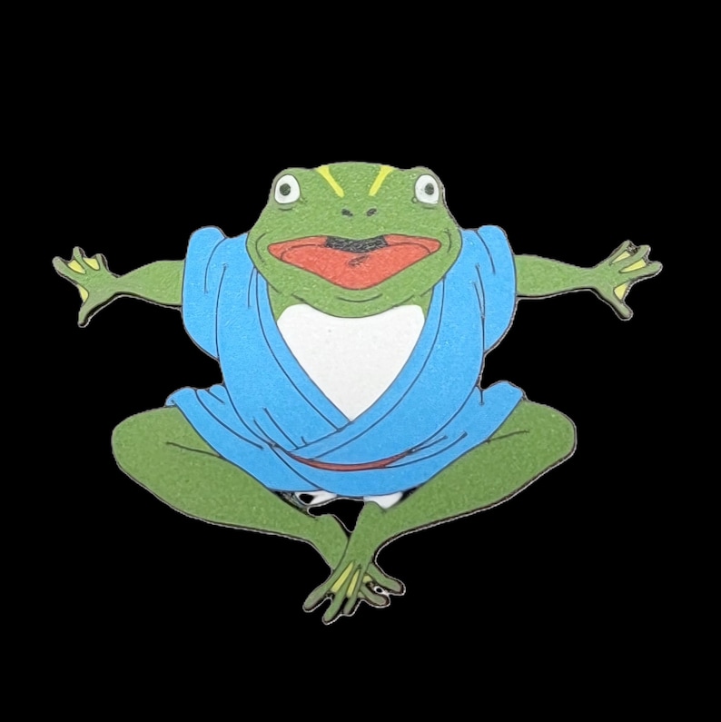 May include: A green frog wearing a blue robe with a white collar, sitting in a meditative pose with arms outstretched.