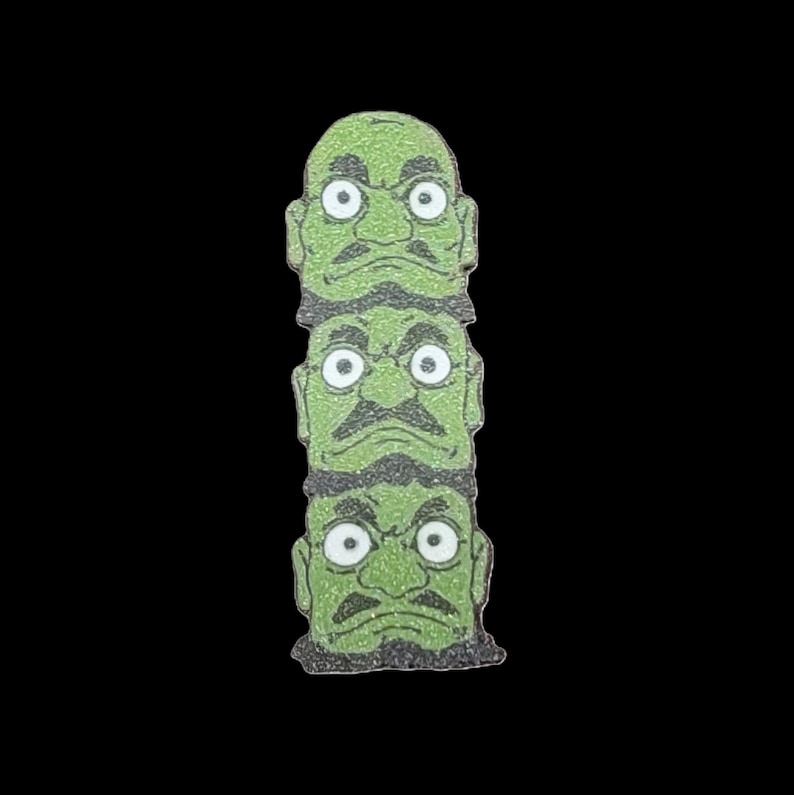 May include: A green three-headed figure with a textured surface. Each head has large eyes, a mustache, and a serious expression.