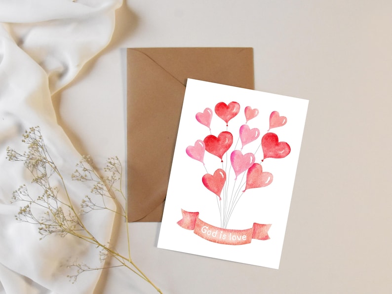 May include: A white card with a watercolor illustration of pink and red heart-shaped balloons with a banner that reads "God is love".