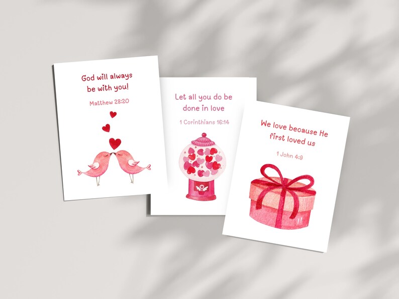 May include: Three printable cards with watercolor illustrations and bible verses about love. The first card features two pink birds kissing with red hearts. The second card shows a pink gumball machine filled with red hearts. The third card has a pink gift box with a red ribbon. The bible verses are Matthew 28:20, 1 Corinthians 16:14, and 1 John 4:9.