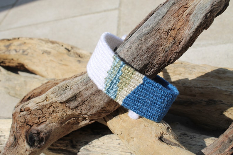 Handwoven bracelet-half white and half ocean blue base with blue, green, beize elements in center image 1