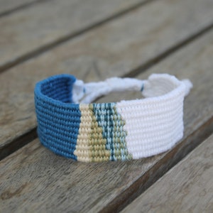 Handwoven bracelet-half white and half ocean blue base with blue, green, beize elements in center image 2