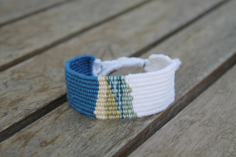 Handwoven bracelet-half white and half ocean blue base with blue, green, beize elements in center image 2