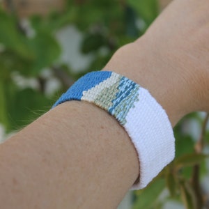 Handwoven bracelet-half white and half ocean blue base with blue, green, beize elements in center image 5