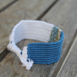 Handwoven bracelet-half white and half ocean blue base with blue, green, beize elements in center image 3