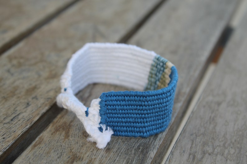 Handwoven bracelet-half white and half ocean blue base with blue, green, beize elements in center image 3