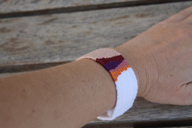 Handwoven bracelet-half white and half beize base with maroon, purple, pink and orange elements in center image 4