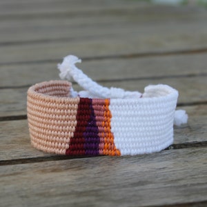 Handwoven bracelet-half white and half beize base with maroon, purple, pink and orange elements in center image 2
