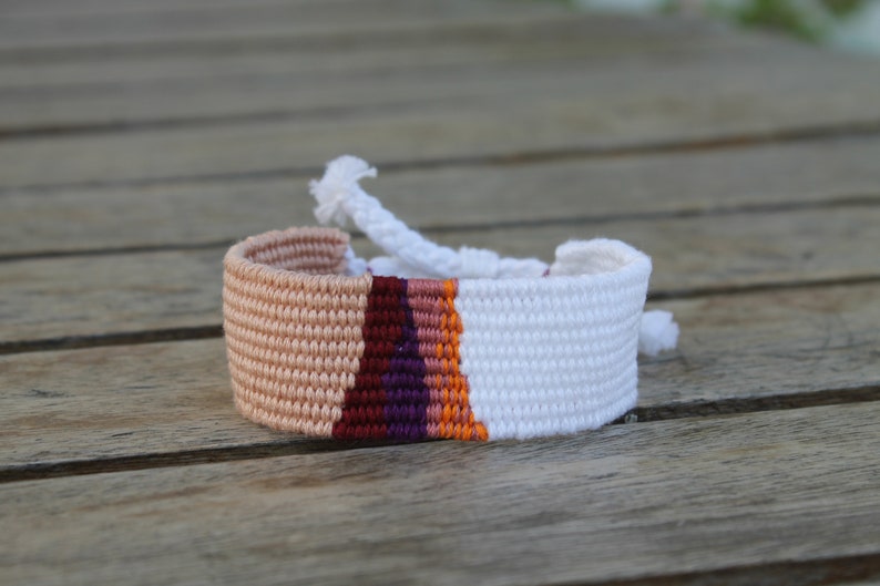 Handwoven bracelet-half white and half beize base with maroon, purple, pink and orange elements in center image 2