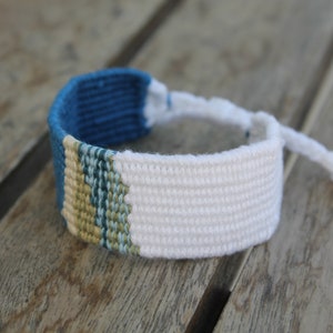 Handwoven bracelet-half white and half ocean blue base with blue, green, beize elements in center image 4