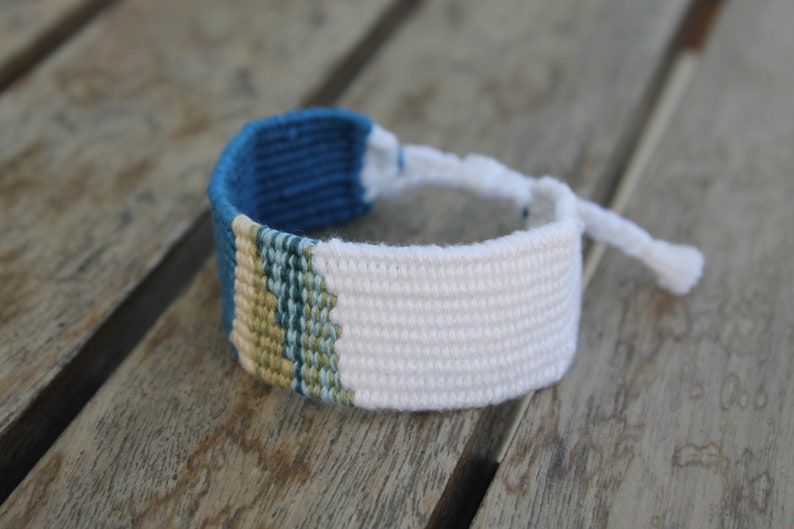Handwoven bracelet-half white and half ocean blue base with blue, green, beize elements in center image 4
