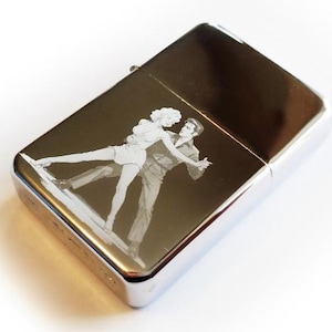 May include: A silver lighter with an engraved image of a couple dancing. The image is in black and white and shows a man and woman in formal attire.