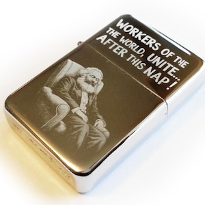 May include: A silver lighter with a gold-toned surface. The lighter features an engraved image of Karl Marx sleeping in a chair. The text "Workers of the World, Unite... After this Nap!" is engraved on the lighter.