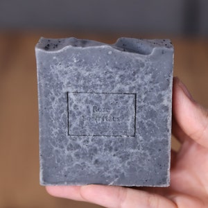 May include: A gray bar of soap with a black label that reads "Rose Soap Notes".