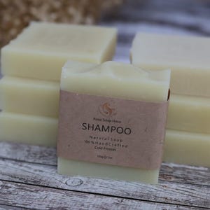 Può includere: Cinque saponette per shampoo naturali impilati. La saponetta in cima ha un'etichetta marrone su cui è scritto "Rose Soap Haus Shampoo Natural Soap 100% Handcrafted Cold Process".