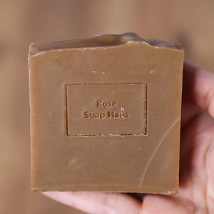 May include: A brown bar of soap with the text "Rose Soap Haus" embossed on the front.
