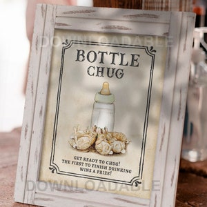 May include: A white framed sign with the text "BOTTLE CHUG" in black. The sign features a baby bottle with a white cap and a group of four baby bunnies. The text below the image reads "GET READY TO CHUG! THE FIRST TO FINISH DRINKING WINS A PRIZE!"