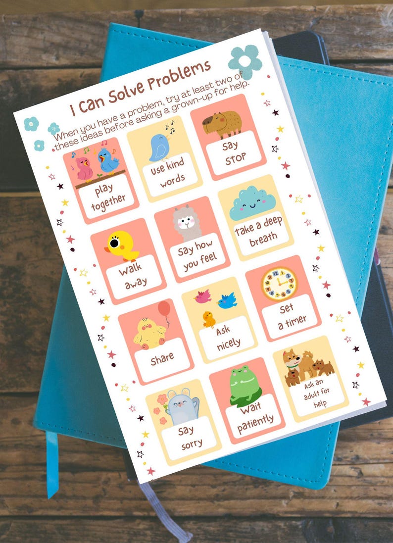 May include: A colorful educational chart titled "I Can Solve Problems" with illustrated tips like "Play Together" and "Use Kind Words." The chart is on top of a blue notebook, promoting social-emotional learning for children.