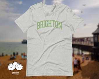 Könnte beinhalten: Ein hellgraues T-Shirt mit dem Wort "BRIGHTON" in Grün auf der Vorderseite.