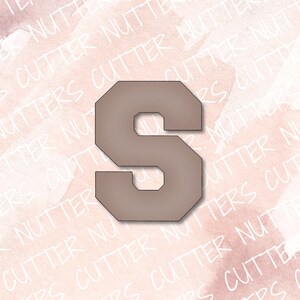 May include: A brown, uppercase letter S cookie cutter. The cutter has a slightly angled, blocky font style.