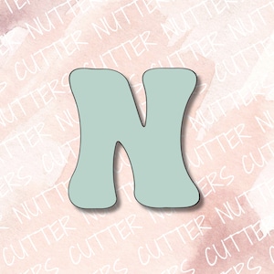 May include: A light blue cookie cutter in the shape of the letter N. The cutter has a rounded, retro style.