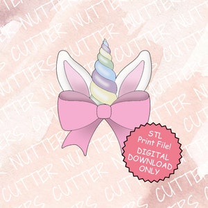 Peut inclure: Un fichier STL téléchargeable numériquement pour un emporte-pièce en forme de licorne avec un nœud et des oreilles roses. La corne de la licorne est un tourbillon de couleurs pastel. Le texte sur le cercle rouge indique "Fichier STL à imprimer ! TÉLÉCHARGEMENT NUMÉRIQUE UNIQUEMENT".