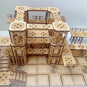 May include: A wooden model of a multi-level building with intricate details and a patterned floor. The model is made of laser-cut wood and features multiple levels, stairs, and walkways.