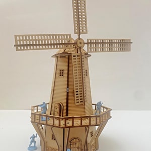 May include: A wooden model of a windmill with a brown base and white blades. The windmill has a small door and windows. There are four small blue figures standing on the platform around the windmill.