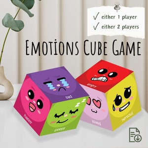May include: A colourful cube game with six sides, each featuring a different cartoon face expressing an emotion: happy, sleepy, sad, loved, angry, and nervous. The game is called "Emotions Cube Game" and can be played by one or two players.