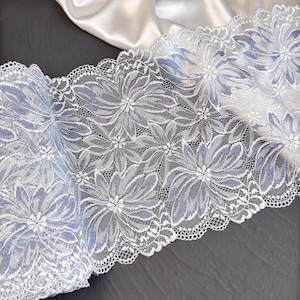 May include: White lace trim with a delicate floral pattern and a light blue undertone.