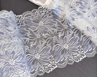 Könnte beinhalten: Weiße Spitzenborte mit einem zarten Blumenmuster und einem hellblauen Unterton.