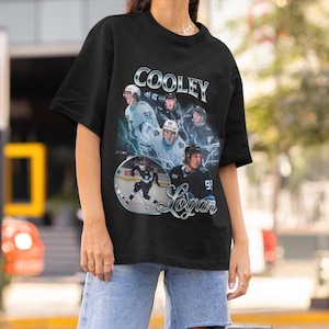 May include: Black t-shirt with a retro design showcasing a hockey player, the name "Cooley", and "Logan" in a decorative font. The graphic includes hockey action shots and the number 92.