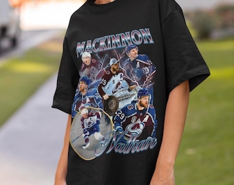 May include: Black t-shirt with a collage of hockey player images, including the name "MACKINNON" in a stylized font. The shirt features multiple images of a hockey player in action, with the name "Nathan" below.