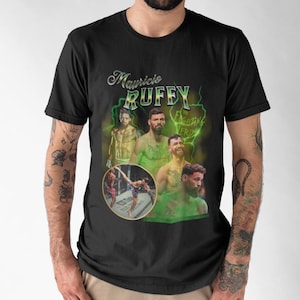 Peut inclure: T-shirt noir avec un imprimé graphique vert et blanc d'un combattant d'arts martiaux mixtes. Le graphique comprend le texte "Mauricio Ruffy" et "Fighting Verde".