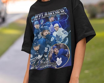 May include: Black t-shirt with a graphic print of hockey players wearing Toronto Maple Leafs jerseys. The text "Nylander Williams" is printed on the shirt.