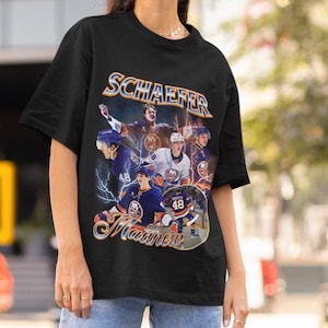 May include: Black t-shirt with a retro design showcasing a hockey player, the name "Schaefer", and the word "Matthews" in a script font. The graphic includes images of the player in action, with the number 48 visible.