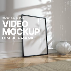 Puede incluir: Una maqueta de marco negro para un video, con el texto "1920x1440px PSD VIDEO MOCKUP DIN A FRAME" en el marco. El marco está en un suelo de madera con una alfombra blanca delante. Hay un jarrón blanco en el suelo a la derecha del marco.