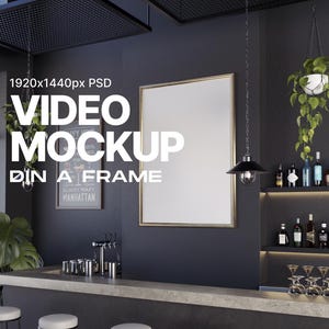 Puede incluir: Una barra negra y gris con una imagen grande, vacía, enmarcada en oro colgada en la pared. La barra tiene una encimera negra con una fila de vasos y botellas en un estante detrás. Hay una planta colgante con hojas verdes y una lámpara colgante negra colgada del techo.